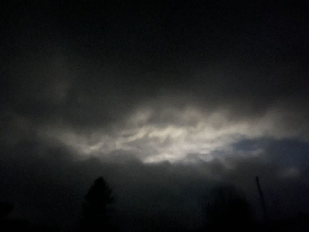 Moonlight breaking through heavy night cloud above dark trees in Mossdale